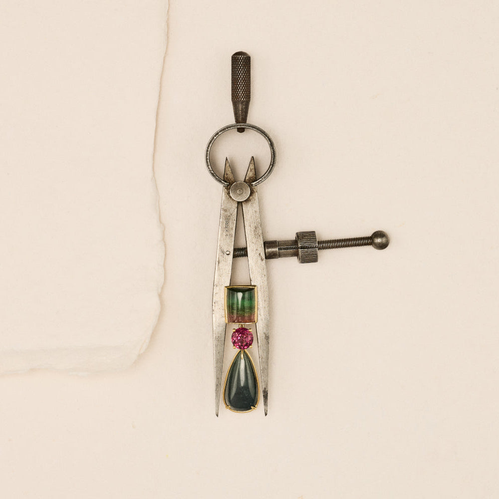 Tourmaline Earrings Photographed with a compass on a textured beige background.